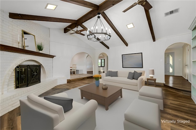 living room featuring lofted ceiling with beams, dark hardwood / wood-style floors, a fireplace, and an inviting chandelier