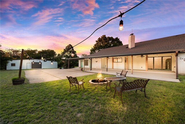 back house at dusk with a lawn, an outdoor fire pit, and a patio