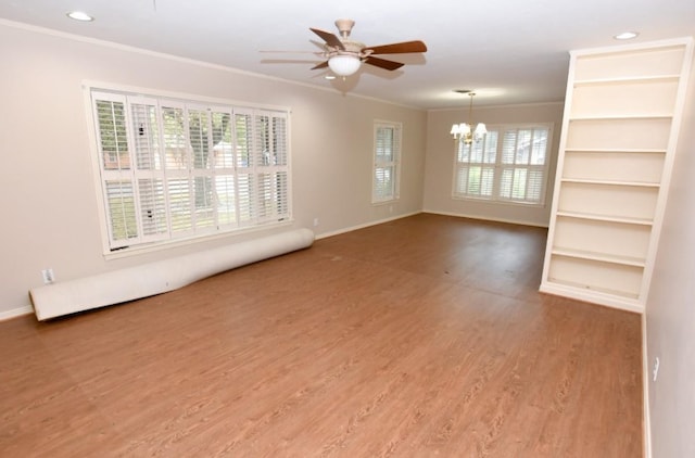 empty room with ceiling fan with notable chandelier, crown molding, wood finished floors, and baseboards