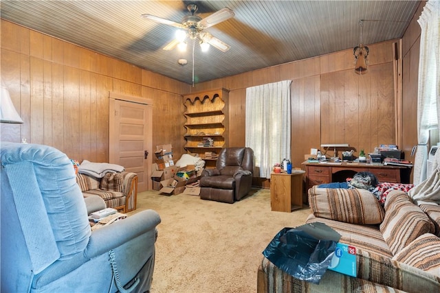 carpeted living room with ceiling fan and wood walls