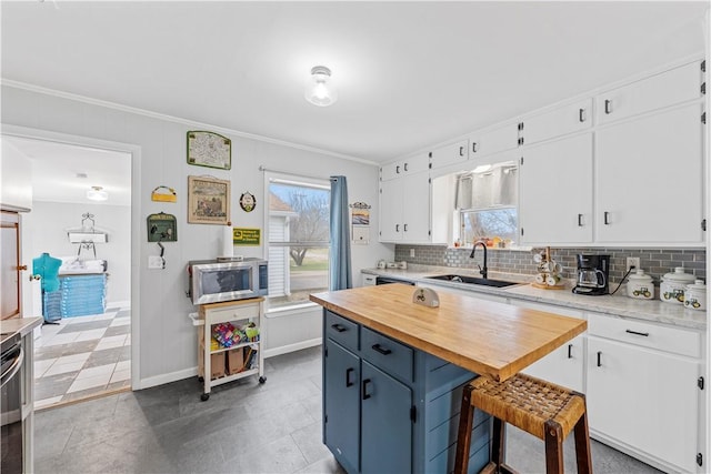 kitchen featuring sink, white cabinets, a kitchen breakfast bar, and decorative backsplash