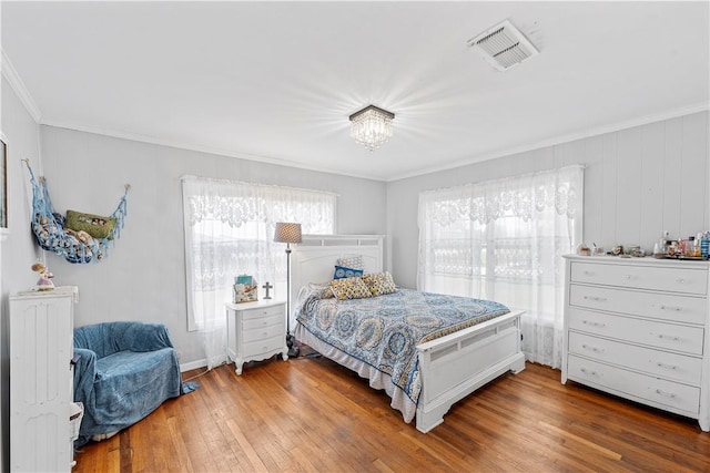 bedroom featuring an inviting chandelier, ornamental molding, and wood-type flooring