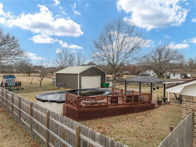 exterior space with a garage, an outbuilding, a gazebo, and a pool side deck