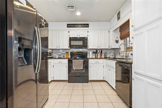 kitchen featuring light tile patterned floors, backsplash, white cabinets, and black appliances