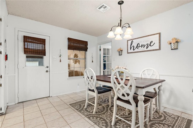 tiled dining area featuring a textured ceiling and a chandelier