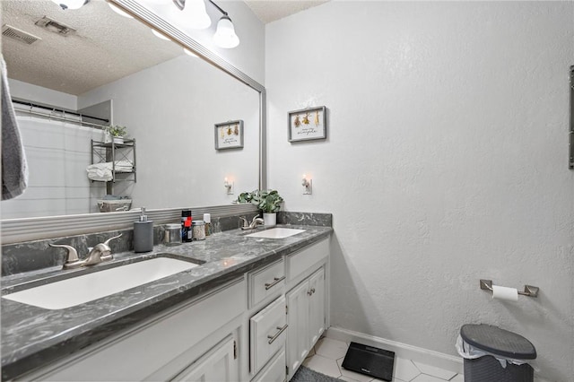 bathroom with a textured ceiling, tile patterned flooring, and vanity