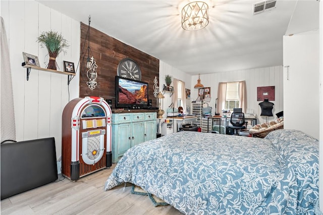 bedroom featuring light wood-type flooring and wooden walls