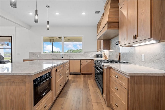 kitchen with light wood-type flooring, hanging light fixtures, a healthy amount of sunlight, and black appliances