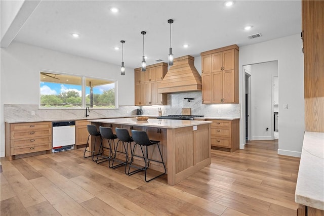 kitchen featuring light wood-type flooring, white dishwasher, a kitchen island, and custom exhaust hood