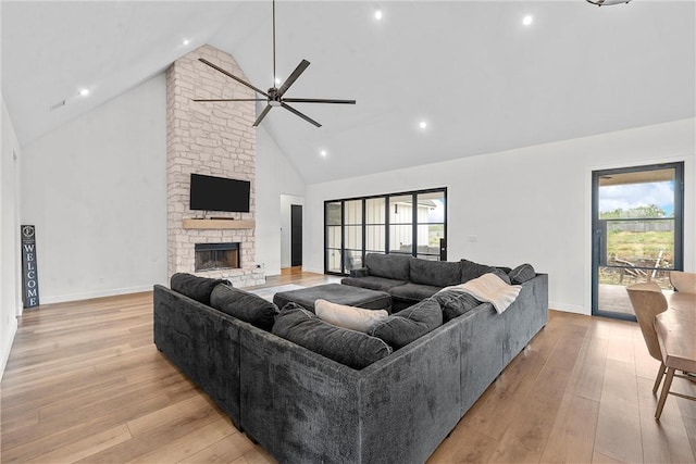 living room featuring ceiling fan, a fireplace, high vaulted ceiling, and light wood-type flooring