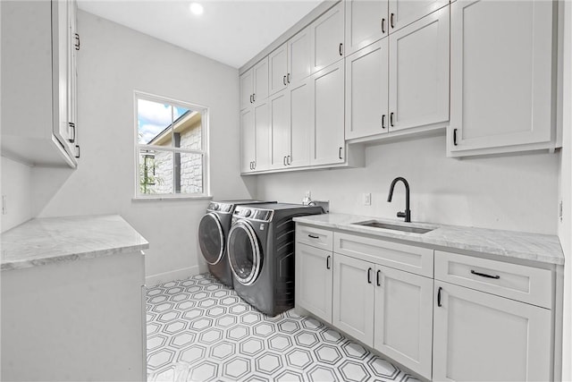 clothes washing area featuring cabinets, washer and dryer, and sink