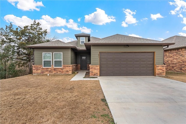 prairie-style home with a front lawn, brick siding, driveway, and an attached garage