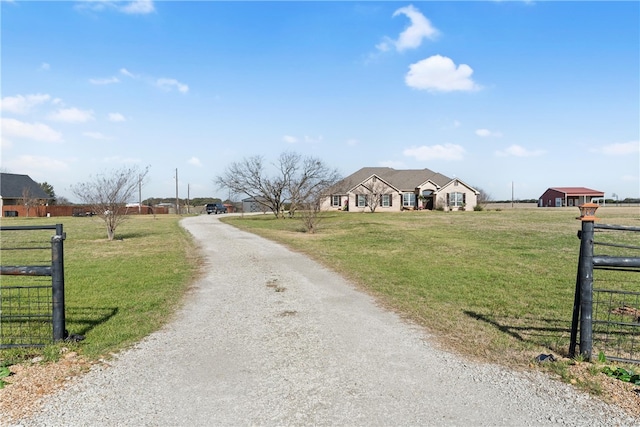 view of road featuring gravel driveway, a rural view, and a gated entry