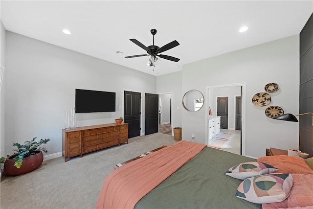 bedroom with ceiling fan, light colored carpet, and ensuite bath