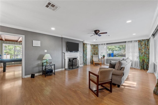 living room with light wood-type flooring, ceiling fan, and ornamental molding