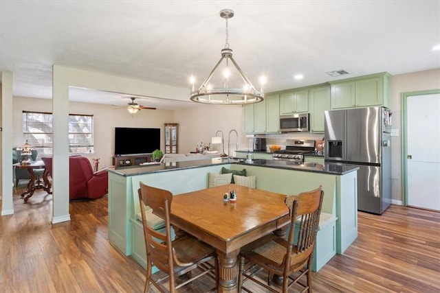 kitchen featuring visible vents, dark countertops, wood finished floors, stainless steel appliances, and green cabinetry