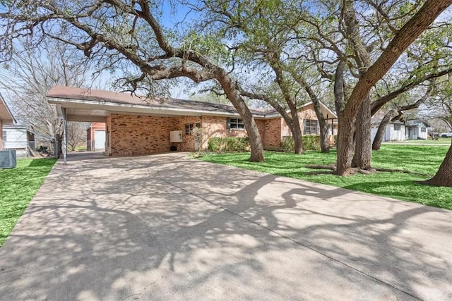 view of front of property with an attached carport, brick siding, driveway, and a front lawn