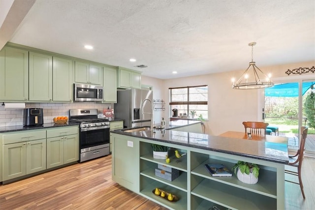 kitchen with open shelves, tasteful backsplash, dark countertops, green cabinets, and appliances with stainless steel finishes