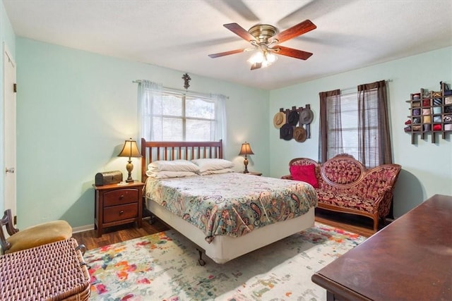 bedroom with a ceiling fan, baseboards, and wood finished floors