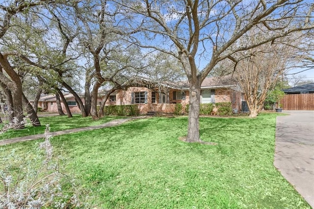 single story home featuring brick siding, a front yard, and fence