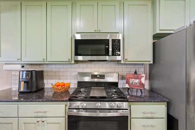 kitchen with stainless steel appliances, dark stone countertops, green cabinets, and tasteful backsplash