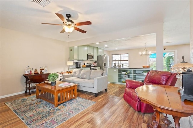 living area with a wealth of natural light, visible vents, light wood-style flooring, and baseboards