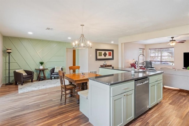 kitchen with open floor plan, a sink, stainless steel dishwasher, and wood finished floors