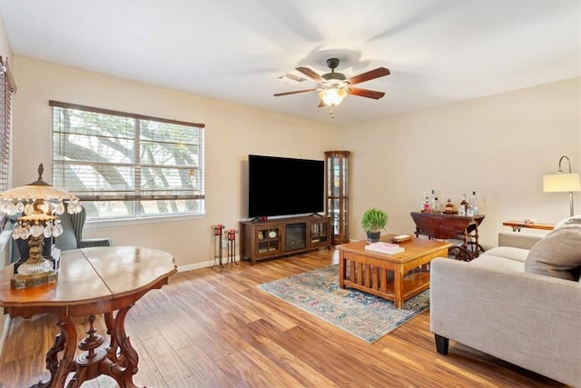 living area featuring baseboards, light wood-style flooring, and a ceiling fan