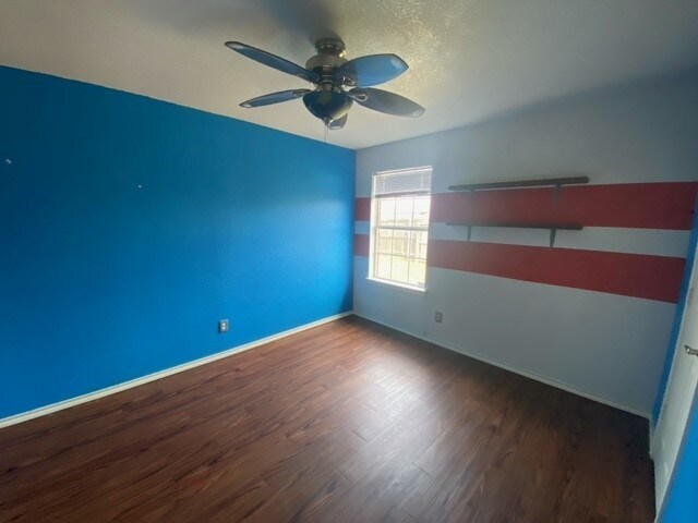 empty room with ceiling fan and dark wood-type flooring