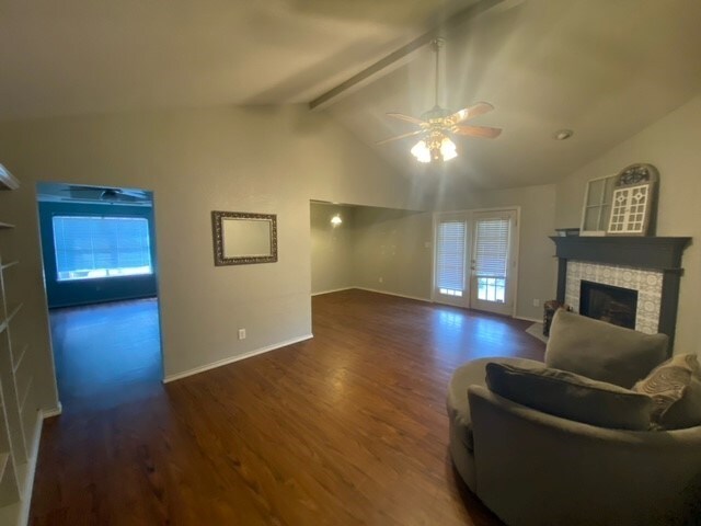 living room featuring french doors, lofted ceiling with beams, dark hardwood / wood-style floors, ceiling fan, and a fireplace