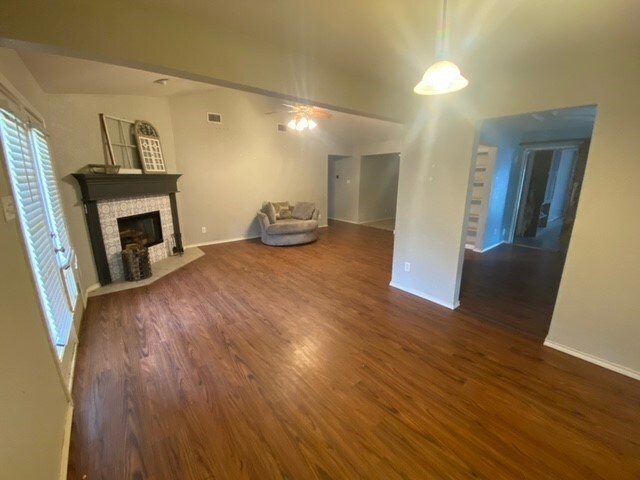 unfurnished living room with ceiling fan and dark wood-type flooring