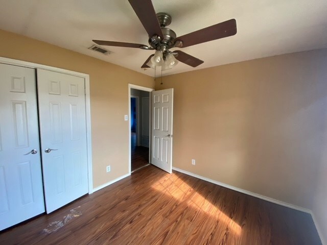 unfurnished bedroom featuring a closet, ceiling fan, and dark hardwood / wood-style floors