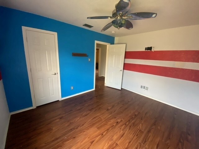 unfurnished bedroom featuring ceiling fan and dark hardwood / wood-style flooring