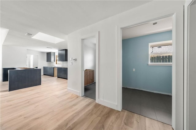 unfurnished living room with a skylight and light hardwood / wood-style floors