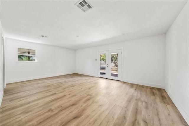 empty room featuring french doors and light hardwood / wood-style flooring