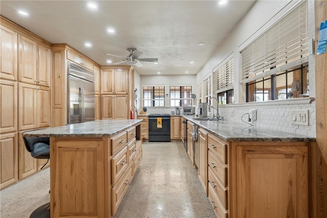 kitchen featuring sink, stainless steel built in fridge, light stone counters, kitchen peninsula, and a breakfast bar