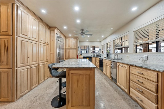 kitchen with ceiling fan, sink, light stone counters, kitchen peninsula, and a breakfast bar