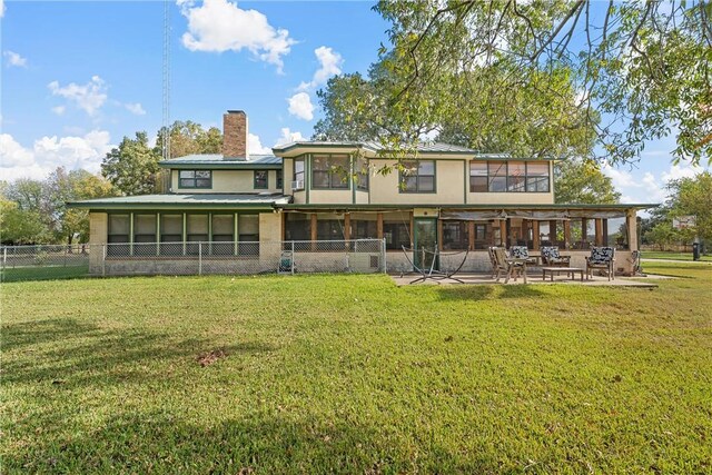 rear view of property featuring a yard, a patio area, and a sunroom