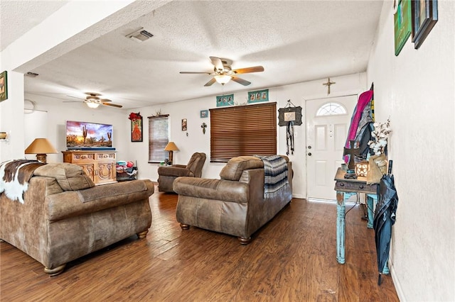 living room featuring ceiling fan, dark hardwood / wood-style flooring, and a textured ceiling