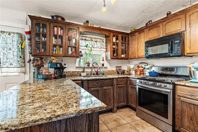 kitchen with sink, light tile patterned floors, a textured ceiling, gas stove, and light stone counters