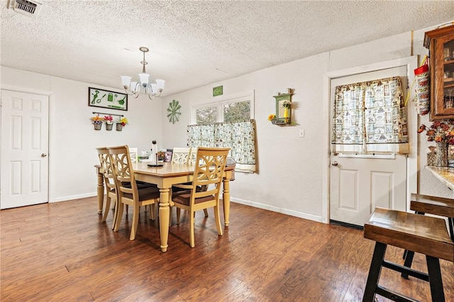 dining room with a chandelier, a textured ceiling, and dark hardwood / wood-style floors