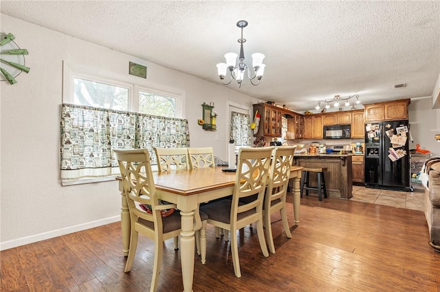 dining space featuring hardwood / wood-style floors, a textured ceiling, and an inviting chandelier