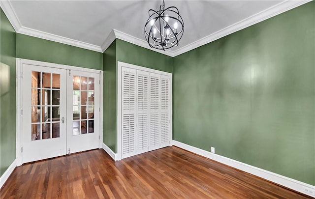 spare room featuring french doors, ornamental molding, a notable chandelier, and wood-type flooring