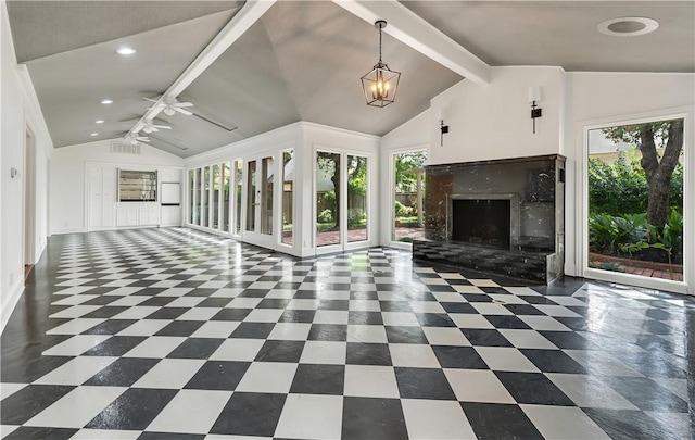 unfurnished living room featuring beam ceiling, a fireplace, plenty of natural light, and ceiling fan with notable chandelier