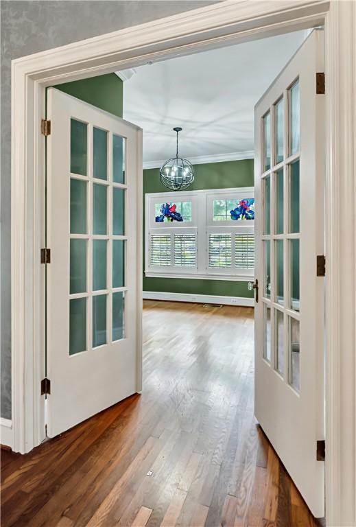 entryway with a chandelier, french doors, ornamental molding, and wood-type flooring