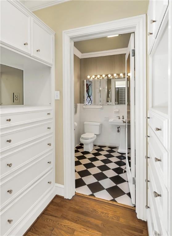 bathroom with wood-type flooring, toilet, and ornamental molding