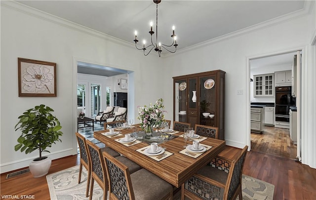 dining room featuring crown molding, dark hardwood / wood-style floors, and an inviting chandelier