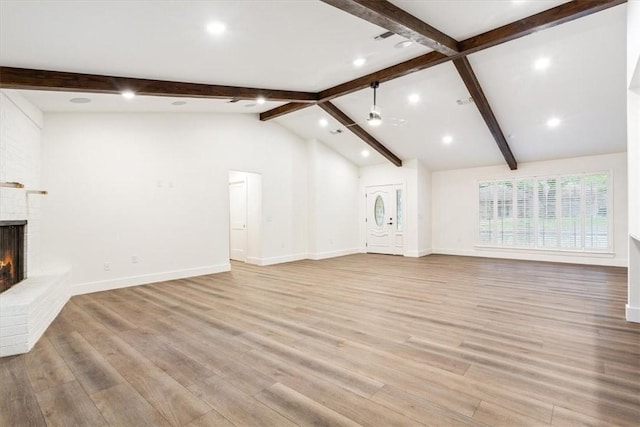 unfurnished living room with lofted ceiling with beams, a brick fireplace, and light hardwood / wood-style flooring