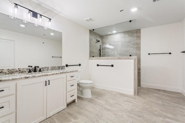 bathroom with tiled shower, vanity, and toilet