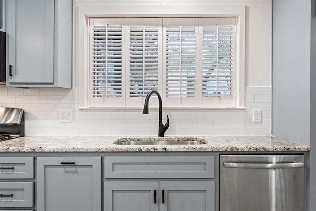 interior details featuring gray cabinets, backsplash, light stone countertops, stainless steel dishwasher, and sink